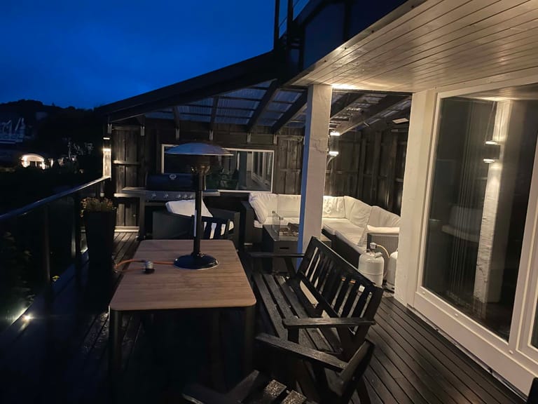 A cozy evening outdoor living space featuring a covered deck or patio area photographed during twilight hours. The space showcases a modern outdoor