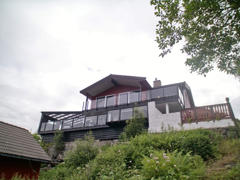 A modern Scandinavian-style hillside residence featuring contemporary architecture with multiple levels built into a sloped terrain. The house showcases a