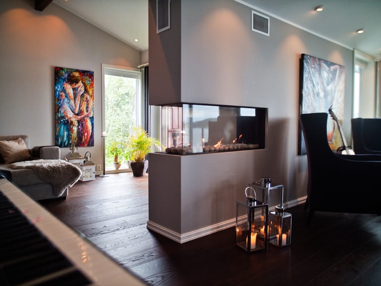 A modern, sophisticated living space featuring a contemporary double-sided fireplace as the central focal point, creating an elegant room divider between