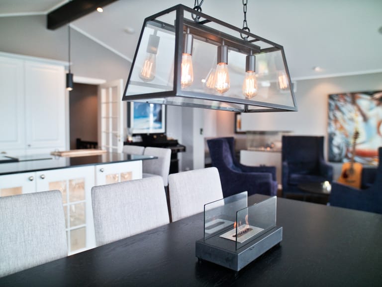 A modern open-concept living space featuring a contemporary industrial-style pendant light fixture as the focal point. The space showcases a sophisticated