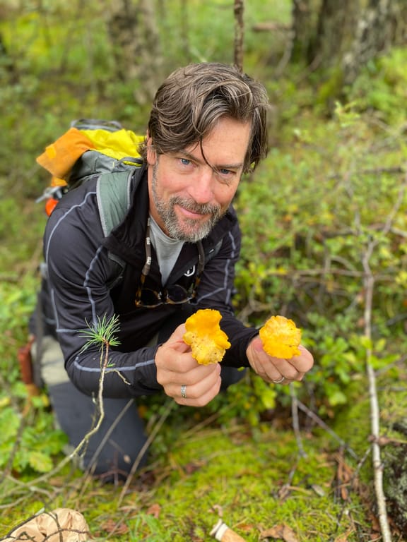 Chris Doyle holding freshly foraged chanterelle mushrooms in the forest